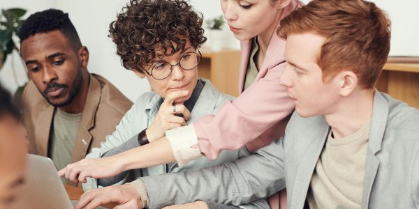 A group of professionals engaged in a collaborative office meeting, discussing ideas with laptops.