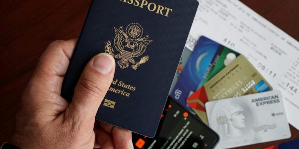 A close-up of a US passport with credit cards, tickets, and a mobile phone on a table.